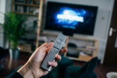 Person holding a TV remote control, illustrating the new Apple TV 4K and its Siri Remote