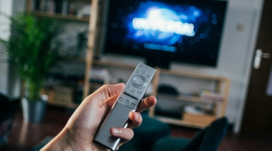 Person holding a TV remote control, illustrating the new Apple TV 4K and its Siri Remote