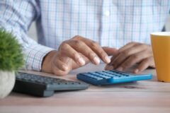 Person using a calculator at a desk, illustrating how interest rate changes affect small business finances