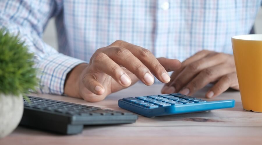 Person using a calculator at a desk, illustrating how interest rate changes affect small business finances